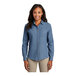 A woman wearing a Port & Company faded blue denim button-down shirt.