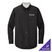 A black Port Authority long sleeve dress shirt on a counter with a logo on the chest.