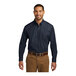 A man wearing a Port Authority river blue long sleeve poplin dress shirt.