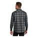 A man wearing a Port Authority black and gray open plaid flannel shirt.