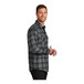 A man smiling in a gray and black plaid Port Authority flannel shirt.