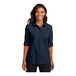A woman wearing a navy Port Authority short sleeve shirt.