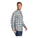 A man wearing a gray and cream plaid Port Authority flannel shirt.