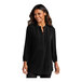 A woman wearing a Port Authority black tunic blouse with short sleeves.