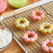 A cooling rack with Fanale Mochi Donuts and powdered sugar on a white background.