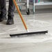 A person using an Ettore floor squeegee with a brush to clean the floor.