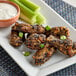 A plate of chicken wings, celery, and ranch dip.