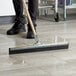 A person using an Ettore steel floor squeegee to clean a floor.
