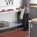 A man in a professional kitchen with a Regency stainless steel undershelf on a work table.