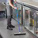 A man using an Ettore floor squeegee to clean a hospital cafeteria floor.