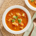 A bowl of Blount Mexican meatball soup with vegetables and herbs on a table.