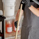 A man in a black apron holding a wooden pole.