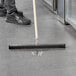 A person cleaning the floor with an Ettore 22" floor squeegee.