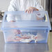 A chef holding a Carlisle blue plastic food storage box with food in it.