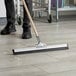 A person using an Ettore aluminum floor squeegee to clean the floor.