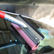 An automotive squeegee with a red handle and an 8-inch cleaning head being used on a car windshield.