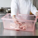 A chef in white gloves holding a Carlisle red food storage container.