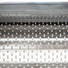 A close-up of the metal surface of a Fama Electric Hard Cheese Grater.
