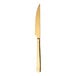 A Sola stainless steel steak knife with a gold handle.