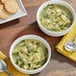 Two bowls of Blount Fine Foods Italian Wedding Soup with meatballs and greens next to a spoon and crackers.