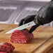 A person using a Victorinox Stiff Fillet Knife to cut meat on a cutting board.