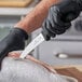 A person in black gloves using a Victorinox blunt tip gutting knife to cut a fish.