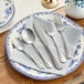 A white plate with Acopa Josette stainless steel flatware on it.