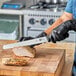 A person using a Victorinox wavy edge slicing knife to cut meat on a cutting board.