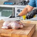 A person using a Victorinox butcher knife to cut a chicken.