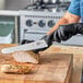 A person in black gloves using a Victorinox slicing knife to cut meat on a cutting board.