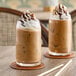 Two glasses of Dr. Smoothie Kona Mocha Coffee with whipped cream on top on a table.