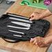 A hand holding a Victorinox knife set in a black bag.