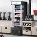 An Avantco black refrigerated air curtain merchandiser full of drinks on a counter.
