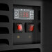 A close-up view of the control panel on a black refrigerated air curtain merchandiser with digital temperature display and two red power switches.