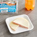 A Cheesewich salami and provolone cheese sandwich on a plate next to a bottle of soda.