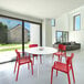 A white table with Siesta Lisa red resin outdoor dining chairs.