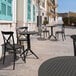 A Siesta Sky black round foldable table and chair set on an outdoor patio.