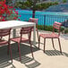 A Siesta Helen Marsala resin outdoor dining chair on a patio overlooking a body of water.