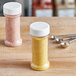 A 7 oz. round plastic spice container with a white lid holding salt and a spoon.