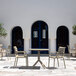 A Siesta Paris taupe resin outdoor dining arm chair on a patio with a table.