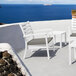 A white Siesta Artemis XL outdoor club arm chair with a Sunbrella taupe cushion on a patio overlooking the ocean.