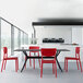 A Siesta Monna red resin outdoor dining chair in a restaurant dining area with a black table.