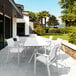 A white Siesta Pacific resin arm chair on a patio with a white table.