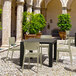 A white Siesta Monna outdoor dining chair on a stone surface with a table.