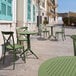 A Siesta Sky olive green round folding table and chairs on a stone patio.