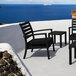 A black Siesta Artemis XL outdoor club arm chair with a black cushion on a patio table.