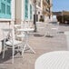 A white Siesta Sky round table and chairs on a stone patio.