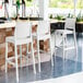 A group of Siesta Maya white bar stools next to a bar.