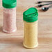 Two round plastic spice containers with green lids on a kitchen counter.