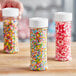 A close up of a round plastic spice container filled with colorful candies.